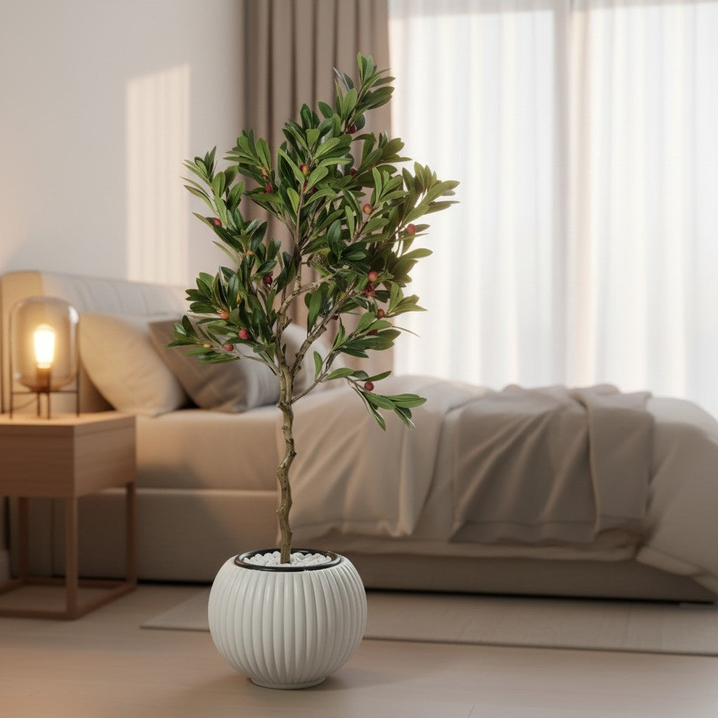 Wadi Home artificial berry tree with green leaves and red berries in a white ribbed pot, placed in a modern bedroom.