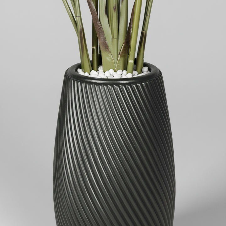 Wadi Home artificial Bird of Paradise plant in a black textured spiral planter with decorative white pebbles
