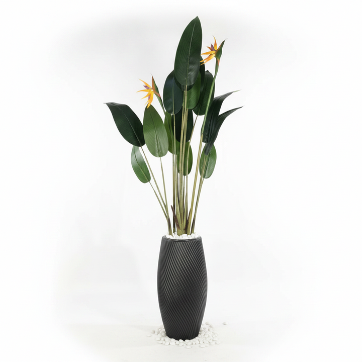 Wadi Home artificial Bird of Paradise plant with green leaves and orange blooms in a black textured spiral planter.