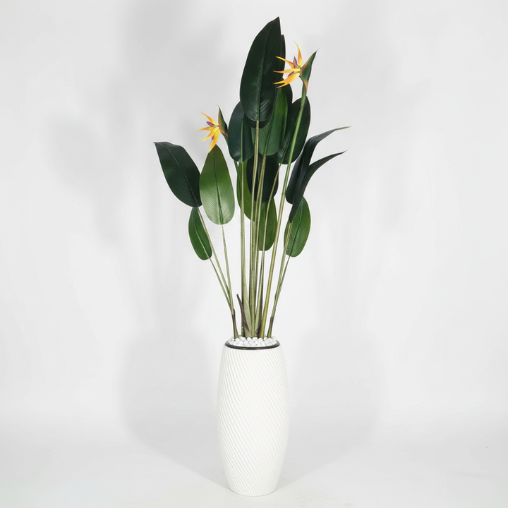 Wadi Home artificial Bird of Paradise plant with green leaves and orange blooms in a textured white floor vase.