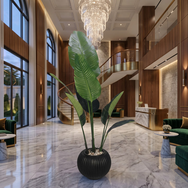 Wadi Home large artificial Bird of Paradise plant in a black ribbed pot, with large green leaves, in a luxury hotel lobby.