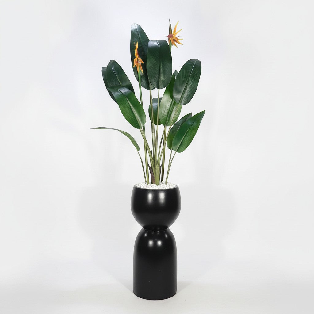 Wadi Home artificial Bird of Paradise plant with green leaves and orange flowers in a modern black hourglass planter.