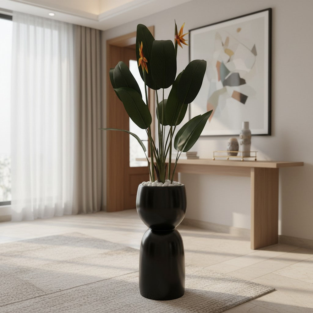Wadi Home artificial Bird of Paradise plant with orange blooms in a modern black sculptural floor planter with stones.