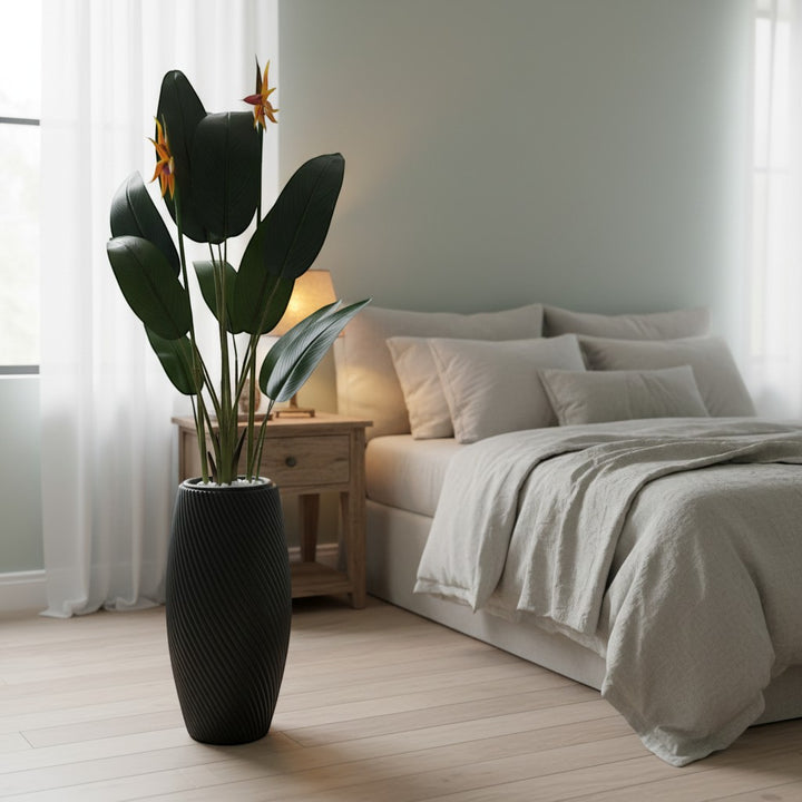 Wadi Home artificial Bird of Paradise plant with deep green leaves and orange blooms in a textured black floor planter.