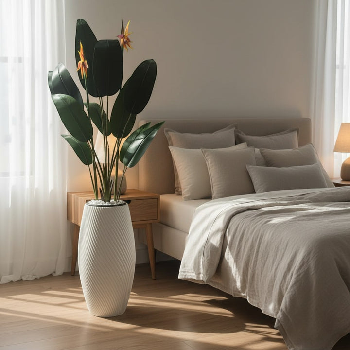 Wadi Home artificial Bird of Paradise plant with vibrant orange blooms in a white spiral textured planter in a bedroom.