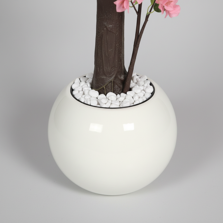 Wadi Home artificial pink blossom tree in a modern white spherical pot with decorative white pebbles at the base