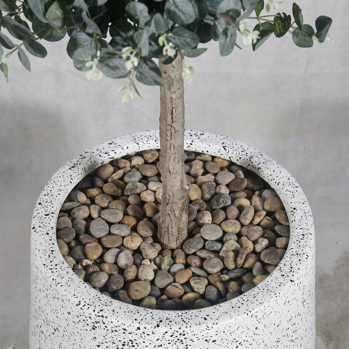 Wadi Home Artificial Eucalyptus Tree with silvery-green leaves and white buds in a speckled white pot with river stones.