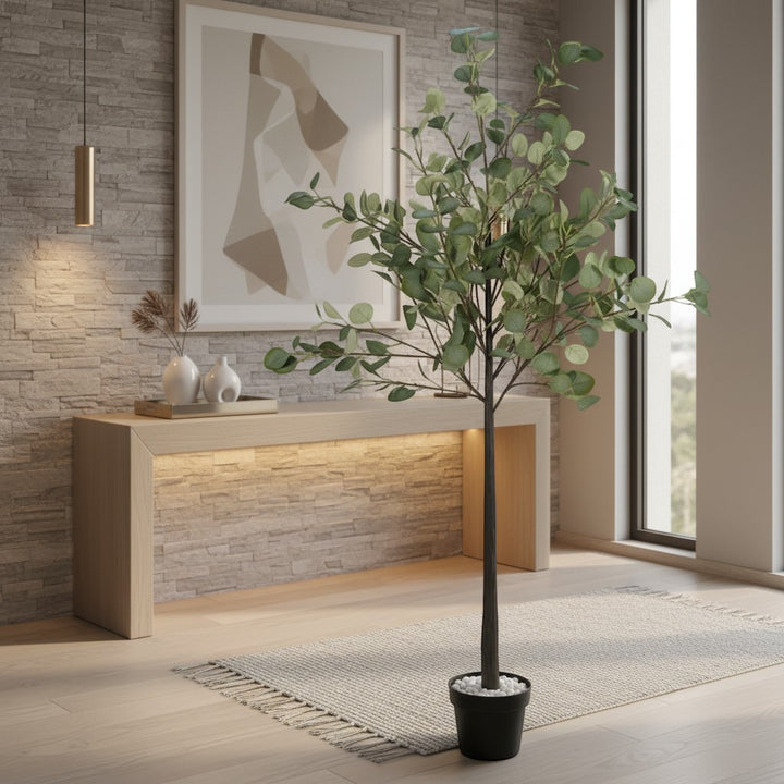 Wadi Home artificial eucalyptus tree in a black pot, featuring realistic green leaves in a modern living room setting.