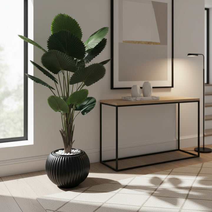 Wadi Home artificial fan palm plant with deep green leaves in a ribbed black ceramic planter with white stones.