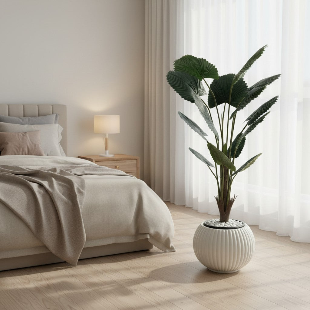 Wadi Home artificial fan palm plant with deep green leaves in a white ribbed planter, placed in a modern bedroom.