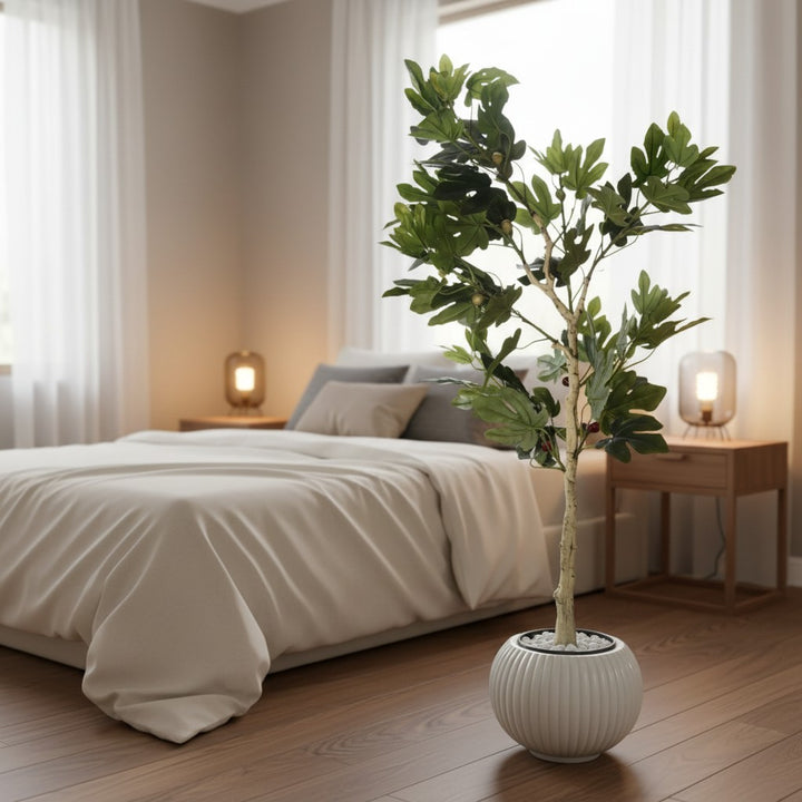 Wadi Home artificial fig tree with lush green leaves and fruit in a ribbed white planter with decorative pebbles.