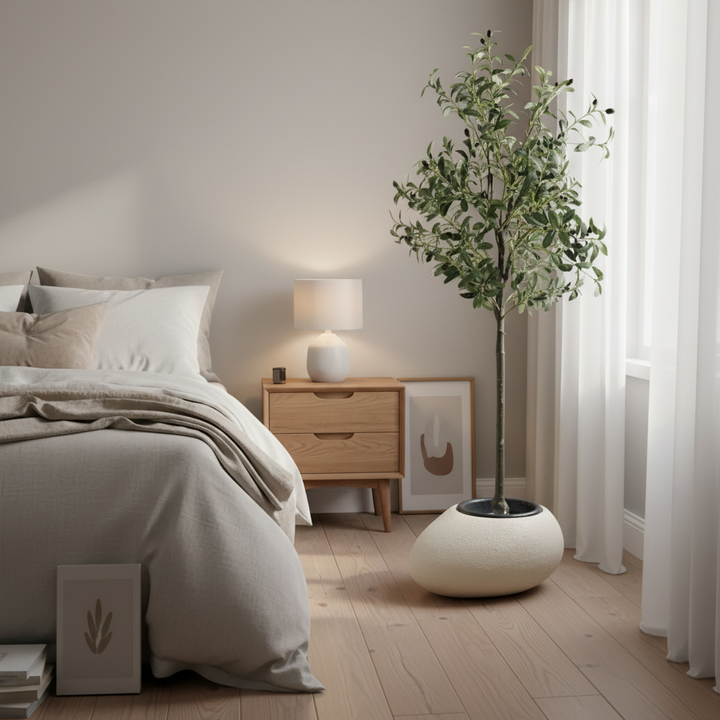 Wadi Home artificial olive tree with silvery-green leaves in a white pot, styled in a modern neutral bedroom.