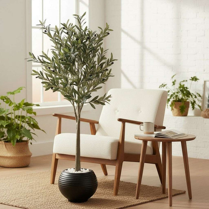 Wadi Home artificial olive tree with green leaves and black olives in a black ribbed planter with white stones.