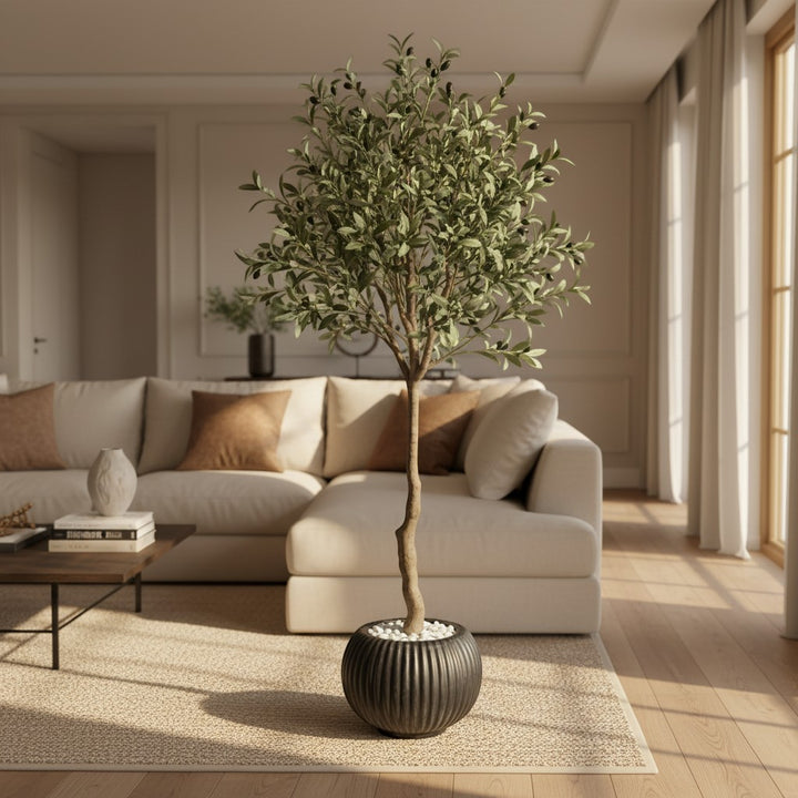 Wadi Home artificial olive tree with green leaves in a black ribbed pot, placed in a bright modern living room.