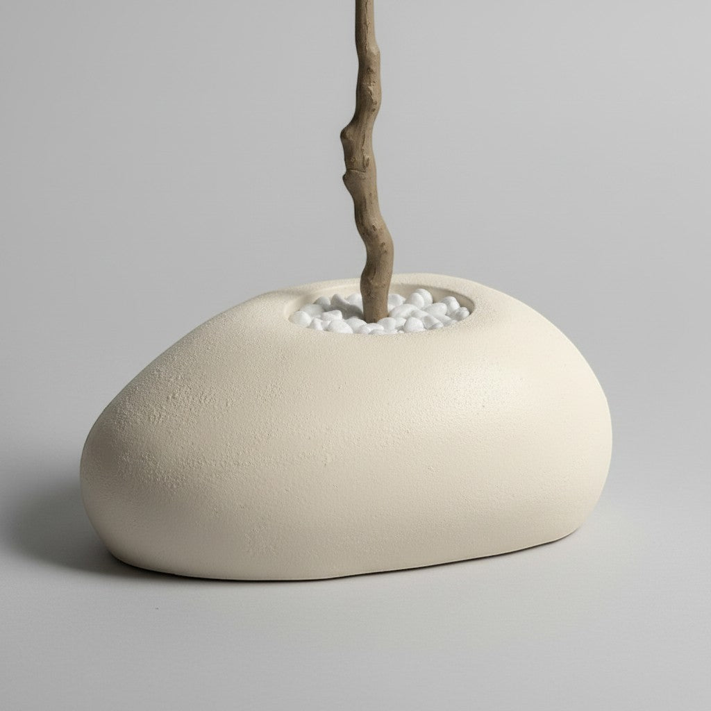 Wadi Home artificial olive tree base with a textured trunk in a smooth organic stone planter filled with white pebbles