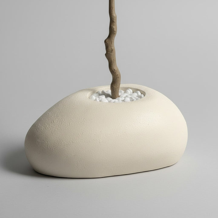 Wadi Home artificial olive tree base with a textured trunk in a smooth organic stone planter filled with white pebbles