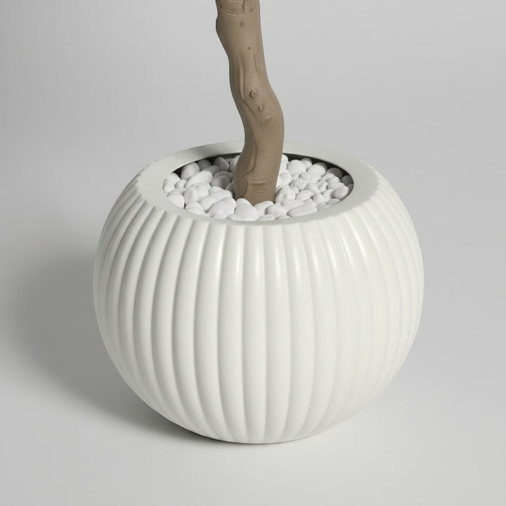 Wadi Home artificial olive tree base featuring a textured brown trunk in a round ribbed white pot with white pebbles.