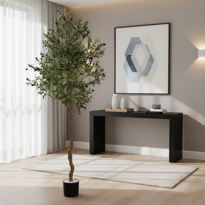 Wadi Home artificial olive tree with green foliage and faux olives in a black pot, placed in a modern living room.