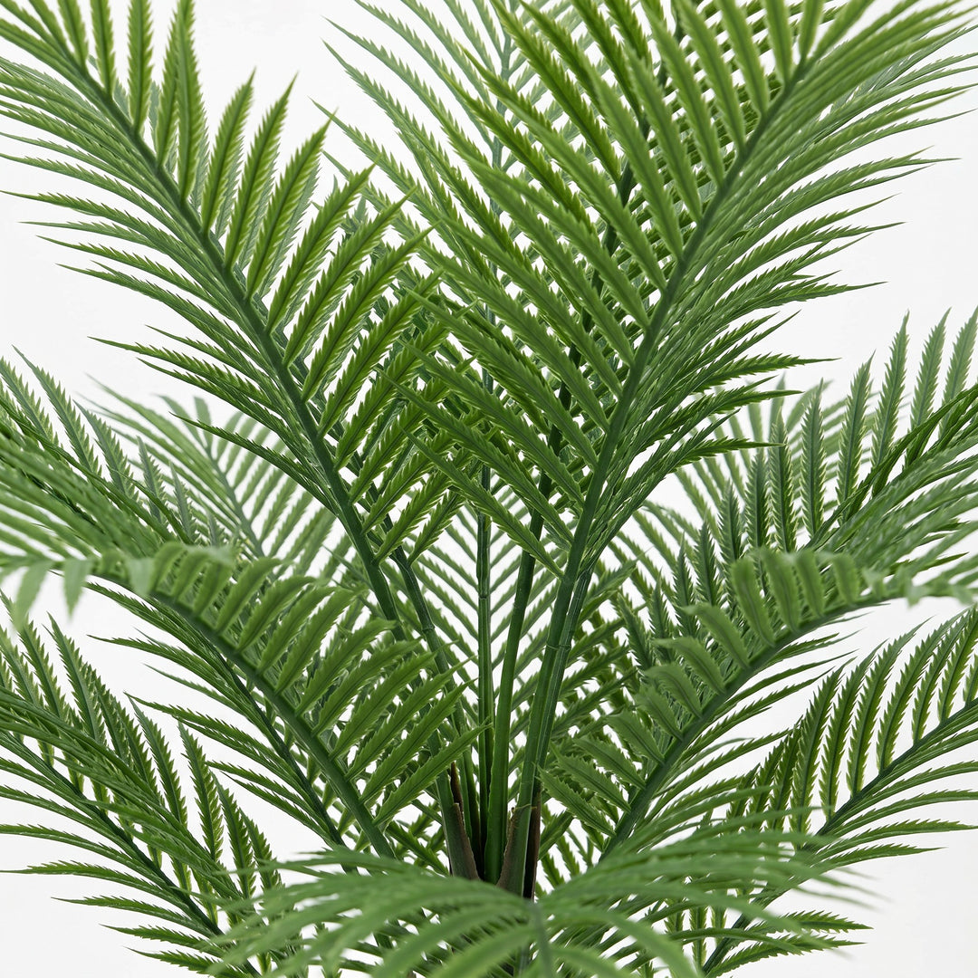 Wadi Home artificial palm plant with lush green fronds in a white fluted pot with white pebbles.
