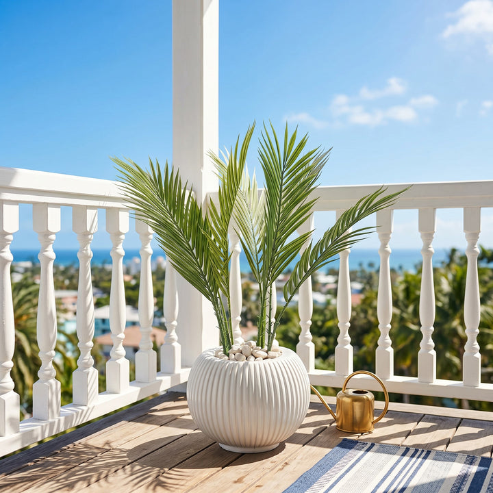 Wadi Home artificial palm plant in a white fluted pot with white pebbles, on a wooden deck.