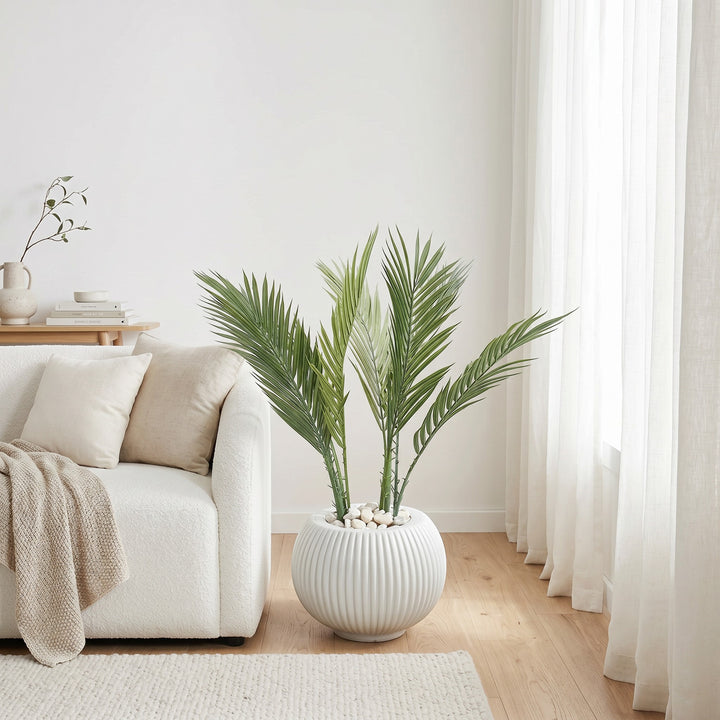 Wadi Home artificial palm plant with lush green fronds in a white fluted pot with white pebbles.