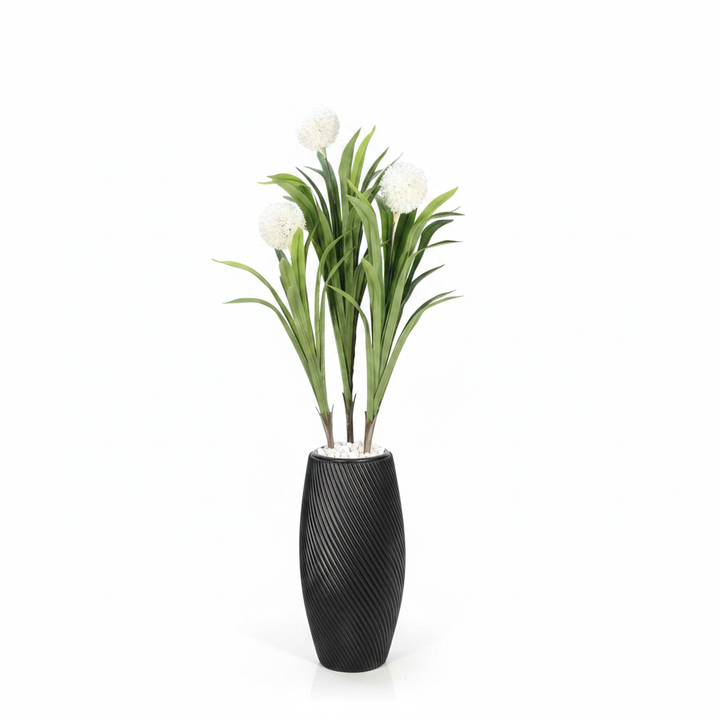 Wadi Home artificial plant with white spherical blooms and green leaves in a black textured spiral vase with stones.