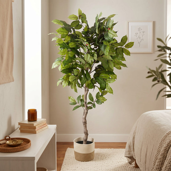 Wadi Home artificial potted tree with green leaves and red berries in a two-toned woven basket in a bedroom setting.