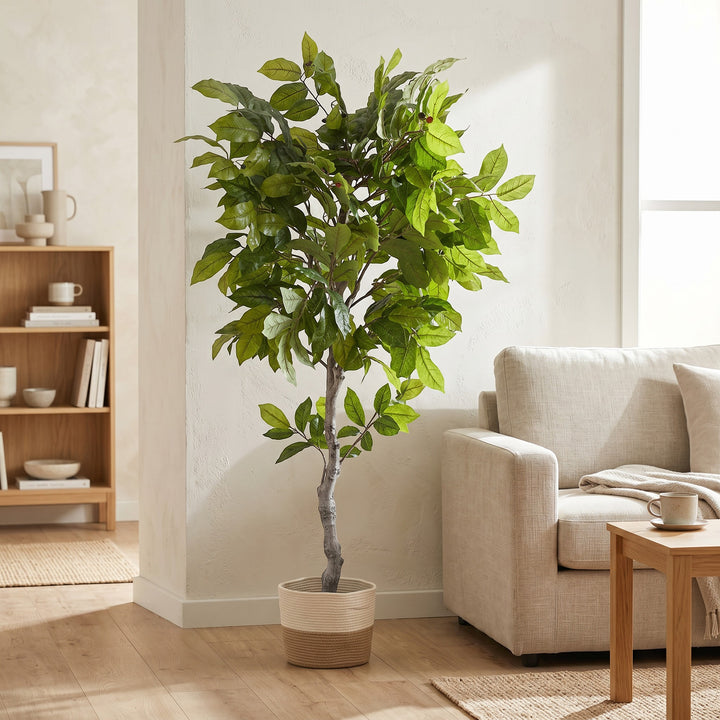 Wadi Home artificial potted tree with lush green leaves and red berries in a two-toned woven basket in a living room.