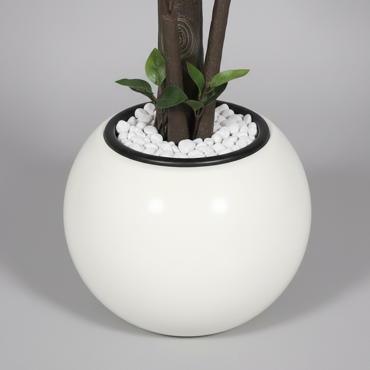Wadi Home artificial tree in a modern white spherical planter with decorative white pebbles at the base