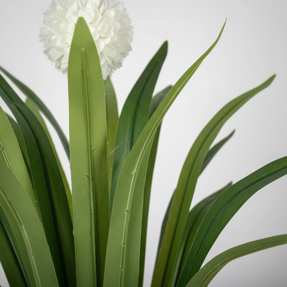 Wadi Home artificial yucca plant with vibrant green leaves and a delicate white flower bloom in a close-up view.