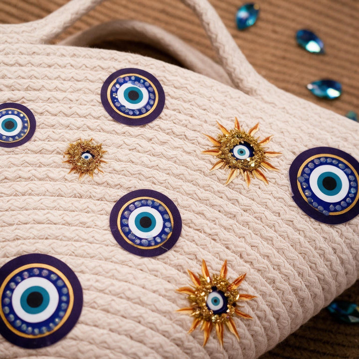 Wadi Home beige rope tote handbag featuring evil eye motifs and gold sun-inspired embellishments for a summer look