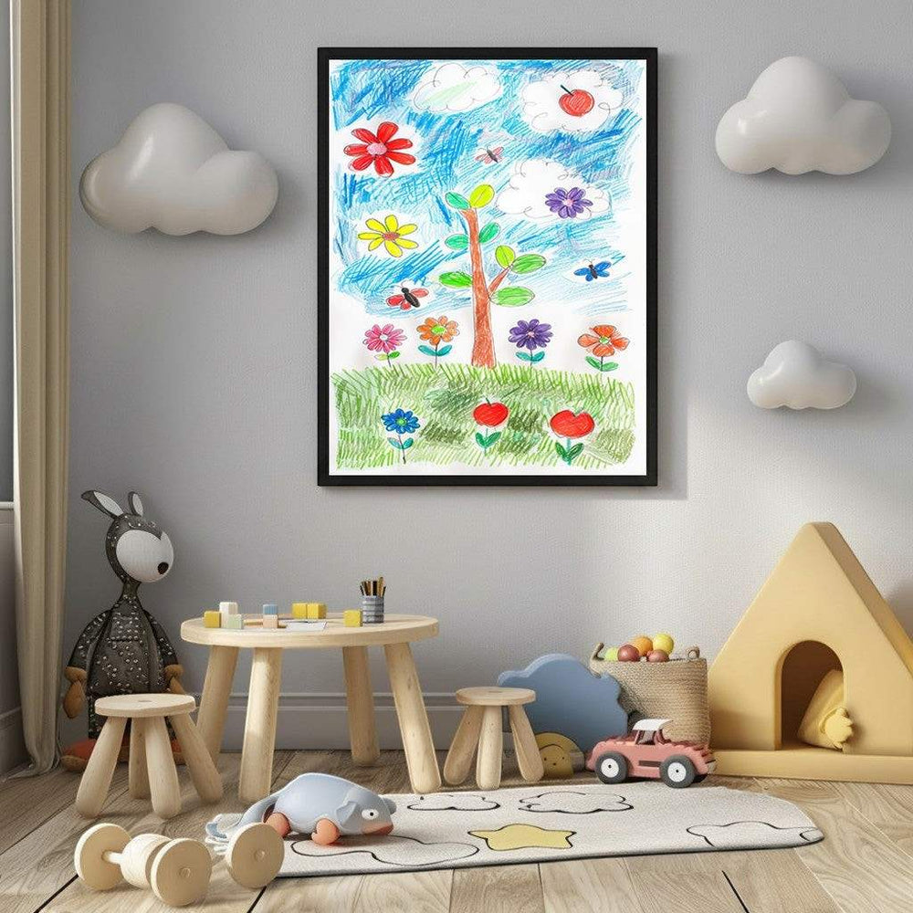 Wadi Home black MDF frame displaying a child's colorful drawing of a tree with flowers and butterflies. The frame is on a grey wall above a wooden table and stools in a child's room.