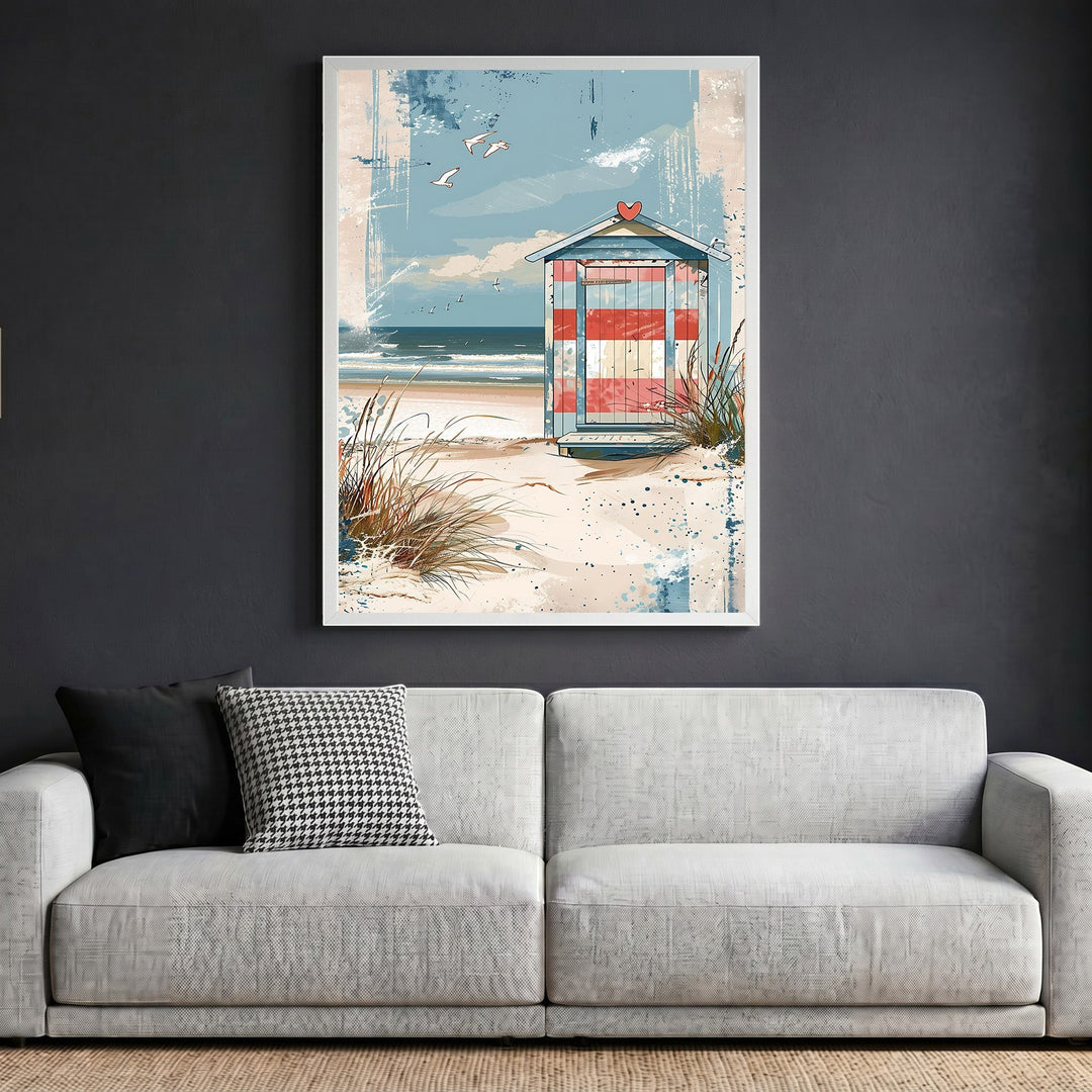 Wadi Home framed coastal wall art featuring a striped beach hut on dunes, displayed above a modern grey sofa.