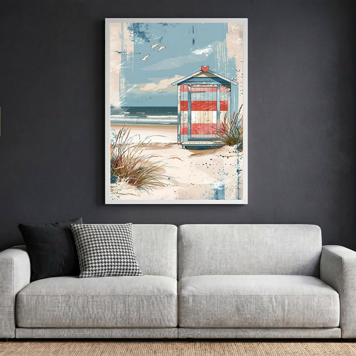 Wadi Home framed coastal wall art featuring a striped beach hut on dunes, displayed above a modern grey sofa.