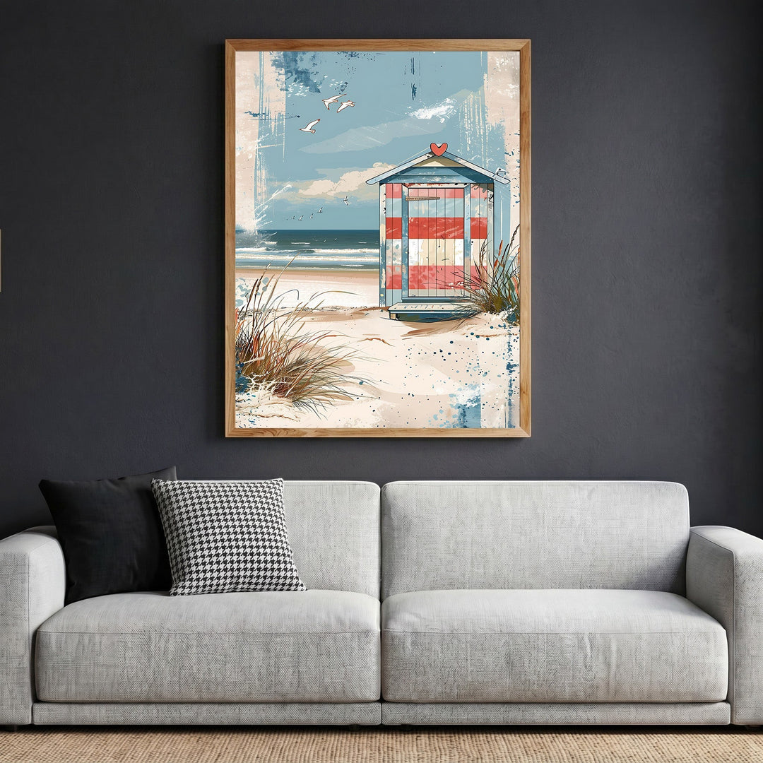 Wadi Home coastal beach house framed art print featuring a striped hut on dunes, displayed above a modern grey sofa.