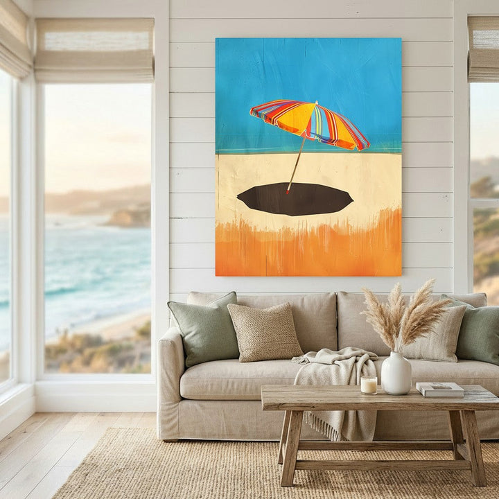 Wadi Home framed wall art featuring a vibrant striped beach umbrella on a sandy shore, displayed in a coastal living room