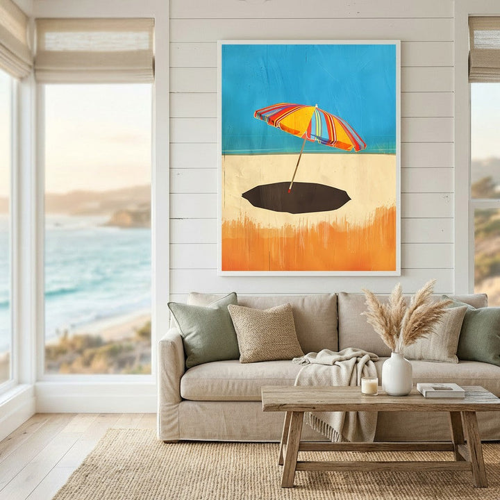 Wadi Home framed coastal wall art featuring a vibrant striped beach umbrella on a sandy shore in a modern living room.