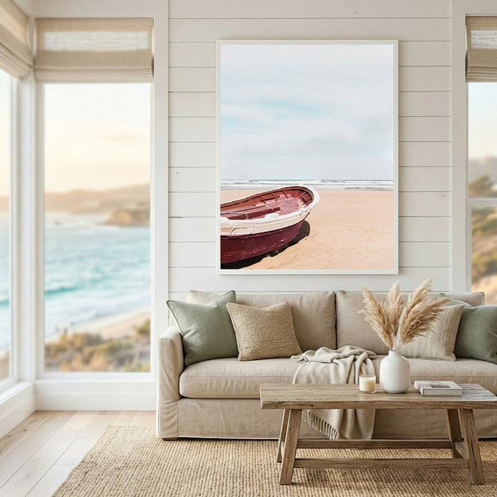 Wadi Home framed wall art featuring a red boat on a sandy beach, displayed in a bright, coastal-style living room.