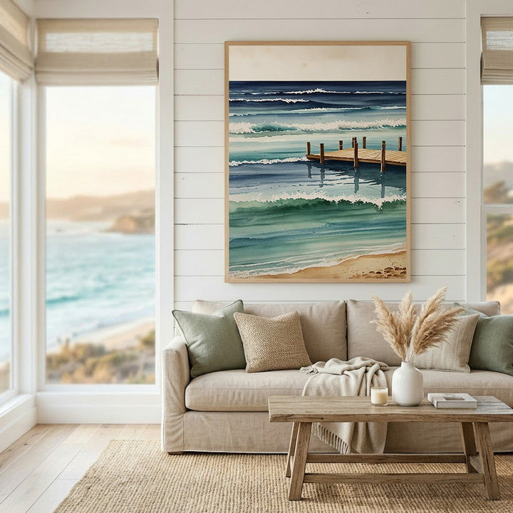 Wadi Home watercolor wall art print of a wooden pier and ocean waves in blue and teal tones hanging above a sofa.