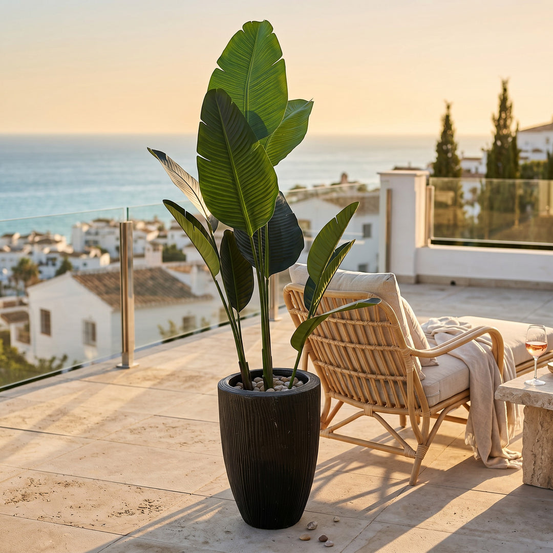 Wadi Home Large Bird of Paradise artificial plant with lush green leaves in a black textured planter on a patio.