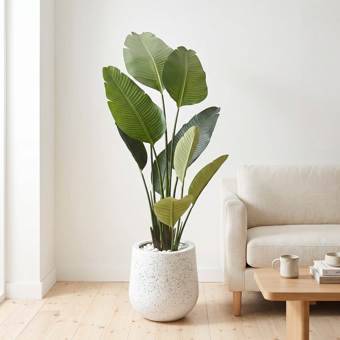 Wadi Home Large Bird of Paradise artificial plant with lush green leaves in a speckled white pot with white stones.