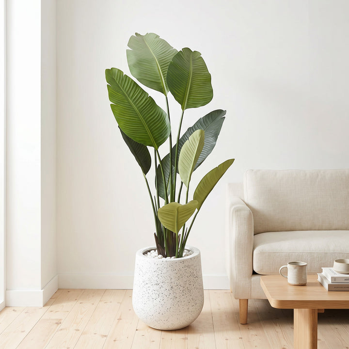 Wadi Home Large Bird of Paradise artificial plant with lush green leaves in a speckled white pot with white stones.