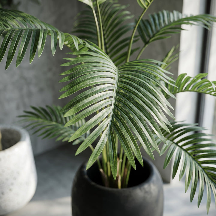 Wadi Home Large Faux Areca Palm Plant in tall black planter with river stones. Lush green fronds.