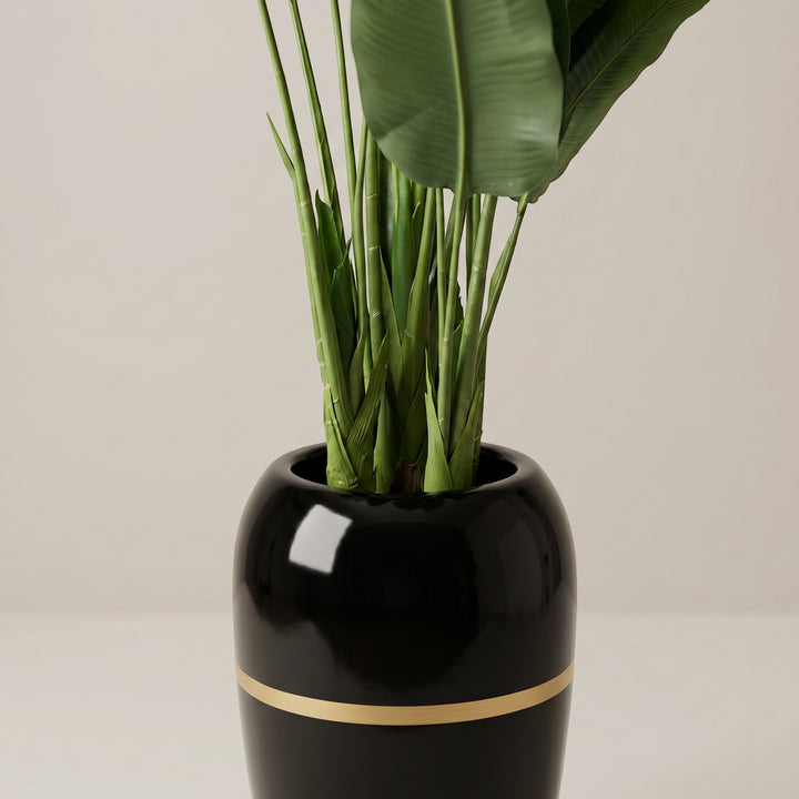 Wadi Home Large Faux Bird of Paradise plant with lush green leaves in a glossy black pot with gold band.