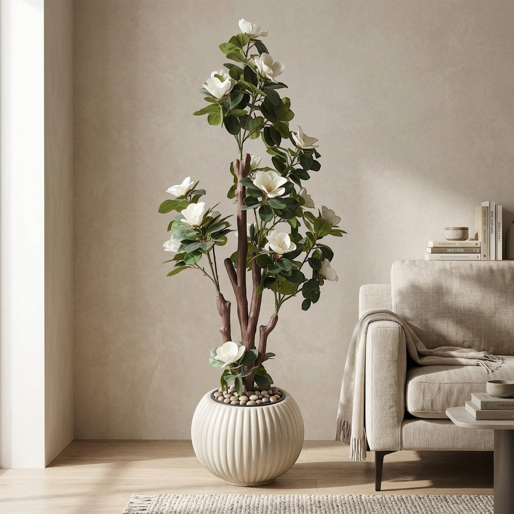 Wadi Home artificial Magnolia Blossom Tree with white flowers and green leaves in a fluted cream planter with stones.