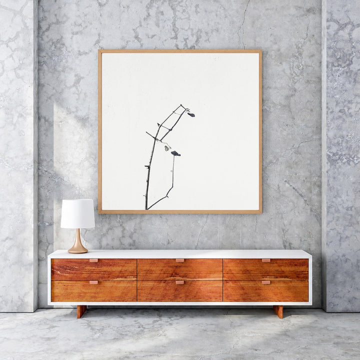 Wadi Home framed minimalist art print of dark branches on a white background, with a light wood frame.