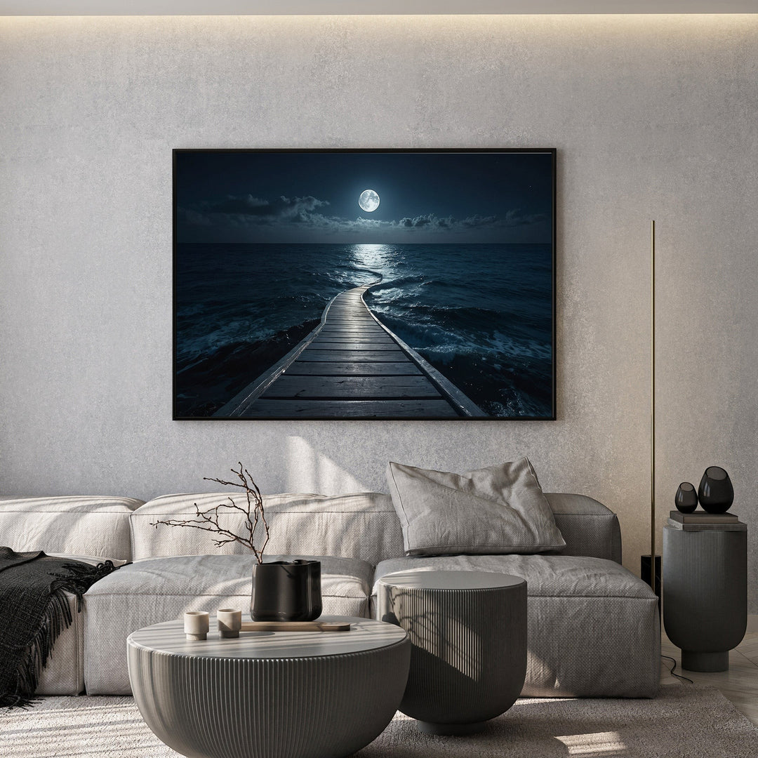 Wadi Home framed wall art of a moonlit ocean pier hanging above a modern grey sofa in a minimalist living room.