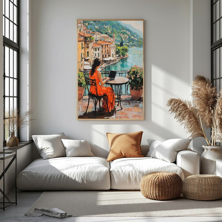 Wadi Home oil painting of a woman in an orange dress working on a laptop by a sparkling blue lake with colorful buildings.