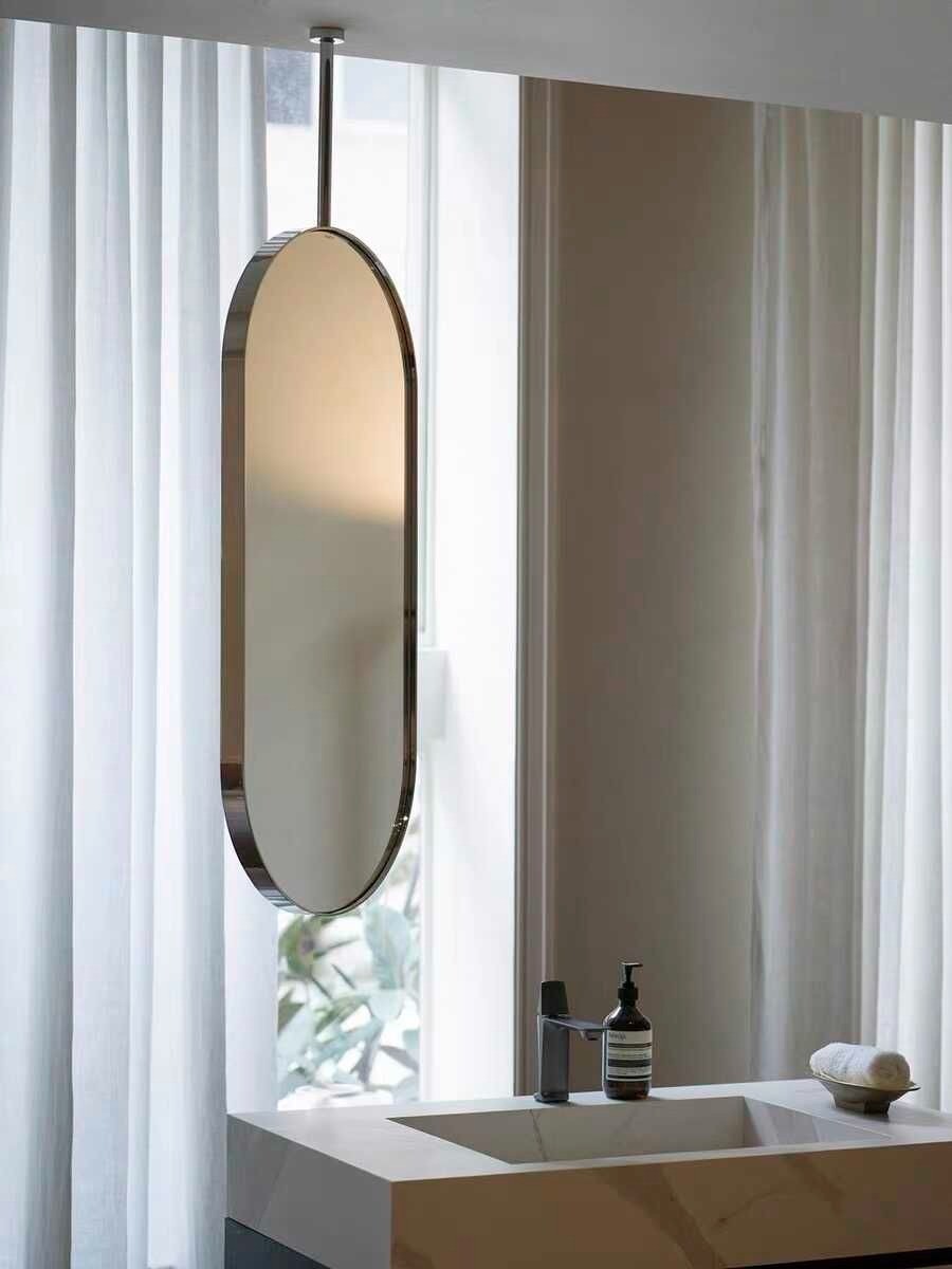 Wadi Home modern oval ceiling mounted bathroom mirror with a sleek metallic frame hanging above a vanity sink.