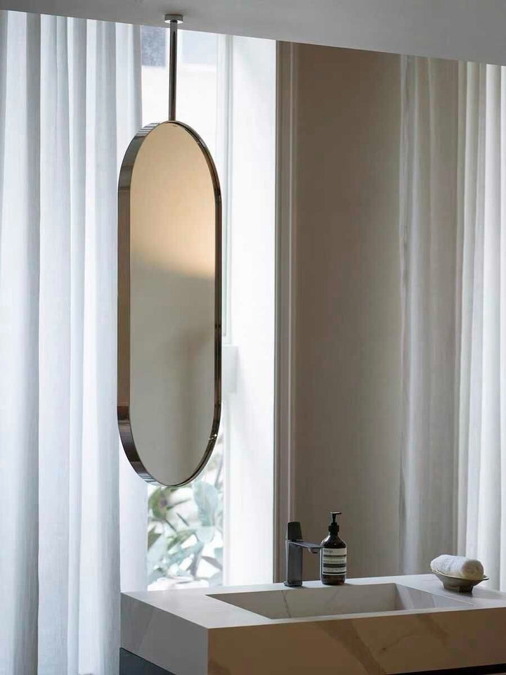 Wadi Home modern oval ceiling mounted bathroom mirror with a sleek metallic frame hanging above a vanity sink.